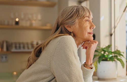 Senior woman smiling while looking out the window at home