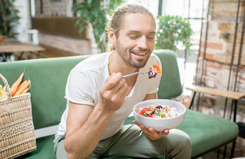 a man smiling while enjoying a meal
