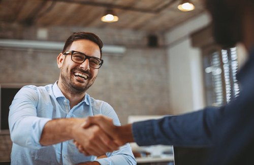 a man smiling while shaking someone’s hand