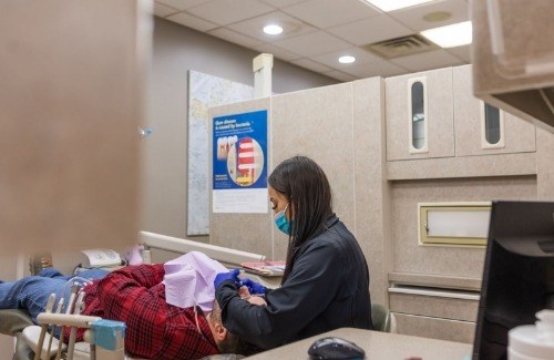 Young woman in green jacket smiling in dental chair