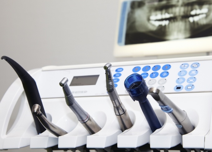 Row of dental instruments in treatment room with x rays of teeth in background