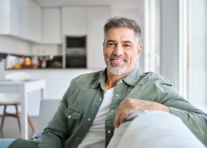 Senior man sitting on couch smiling