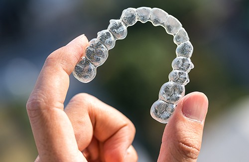 Hand holding an Invisalign aligner