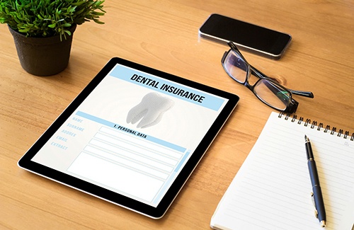 Dental insurance form on tablet next to desk supplies