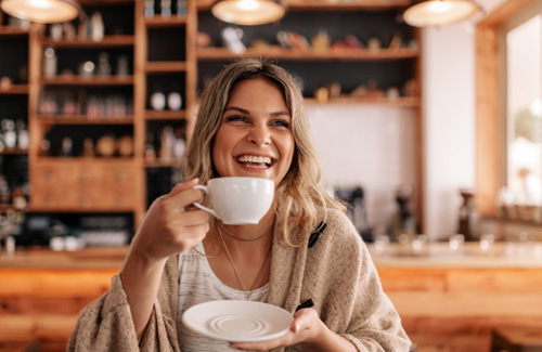Woman smiling while enjoying coffee at restaurant