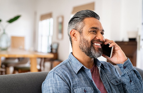Man smiling while talking on phone at home
