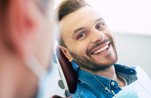 Man smiling at dentist while sitting in treatment chair