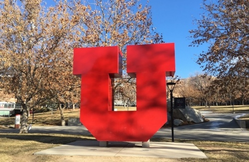 Sculpture of a large red letter U in grassy courtyard