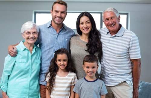 Three generations of smiling family in room with a window