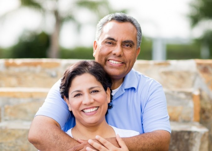 Older man and woman embracing and smiling after replacing missing teeth in West Jordan