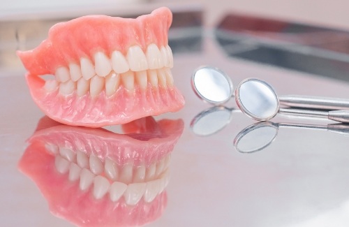 Full dentures on tray next to two dental mirrors