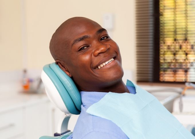 Smiling man leaning back in dental chair during preventive dentistry checkup