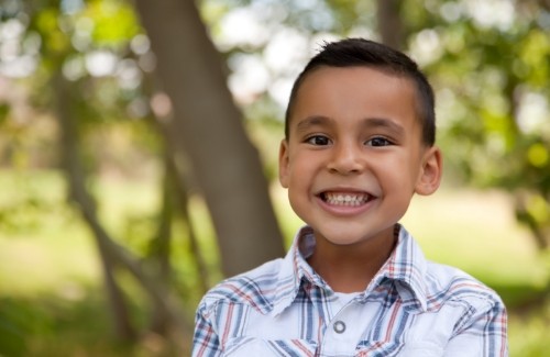 Young boy smiling with trees in background