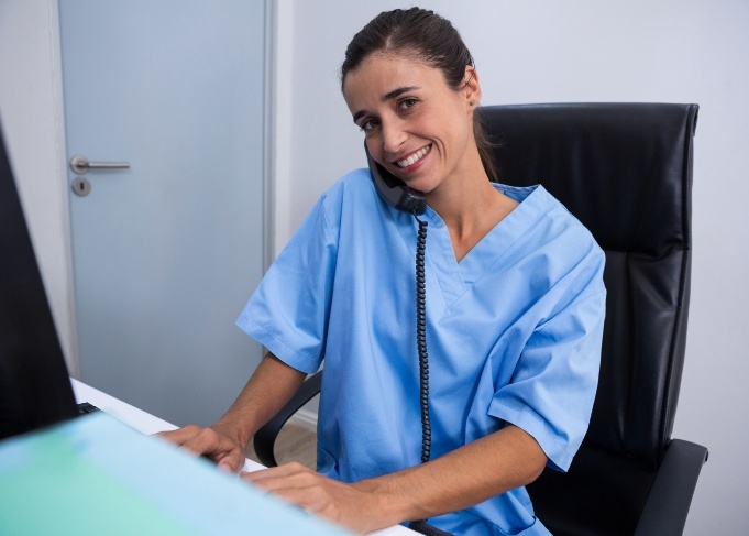 Dental team member sitting at desk and answering phone