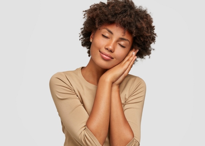 Woman making pillow shape with her hands and pretending to sleep