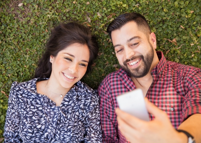 Man and woman looking at phone and watching dentist video testimonials in West Jordan