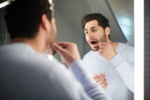Man looking for gum bumps in mirror
