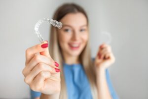 Woman holding Invisalign in foreground.