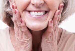 Older woman smiling and showing off white, bright dentures.
