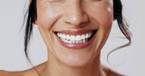 Nose-to-neck view of woman smiling with hair strands falling beside her face